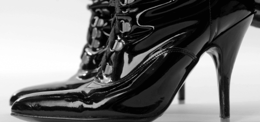 black shiny high-heeled boots on light background as a concept for BDSM kinks involving shoes, feet, and leather